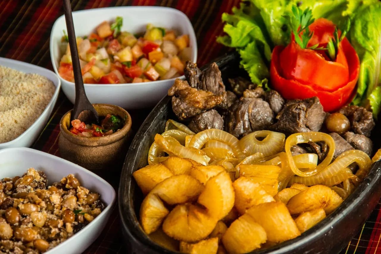 Traditional Brazilian cuisine with meat, fried cassava, beans, salad, and farofa